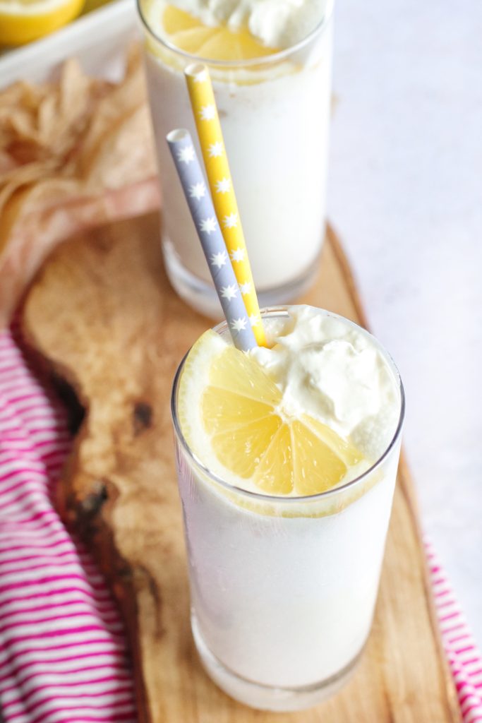 two tall slender glasses filled with copy cat chick fil a frosted lemonade and shown on a small wooden cutting board