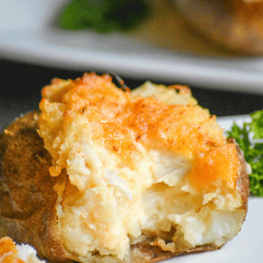 a twice baked crab stuffed potato on a white plate, opened to reveal the filling