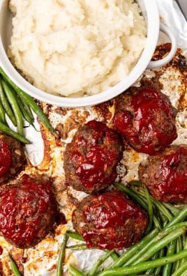 roasted green beans, mini meatloaves, and a bowl of mashed potatoes on a metal sheet pan