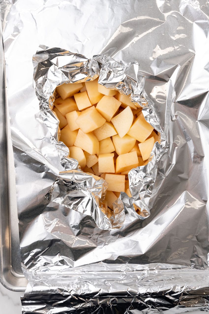 chopped peeled potatoes being wrapped up in aluminum foil