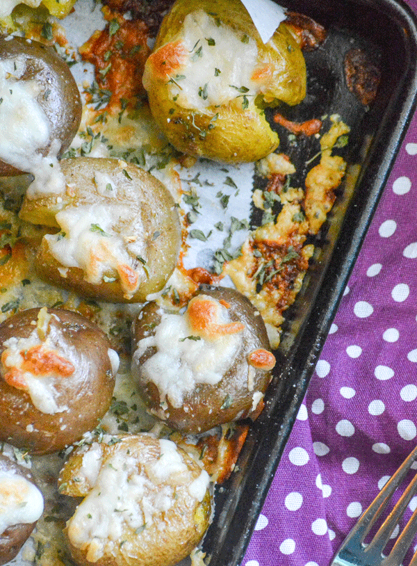 crispy cheese topped smashed potatoes on a parchment lined baking sheet