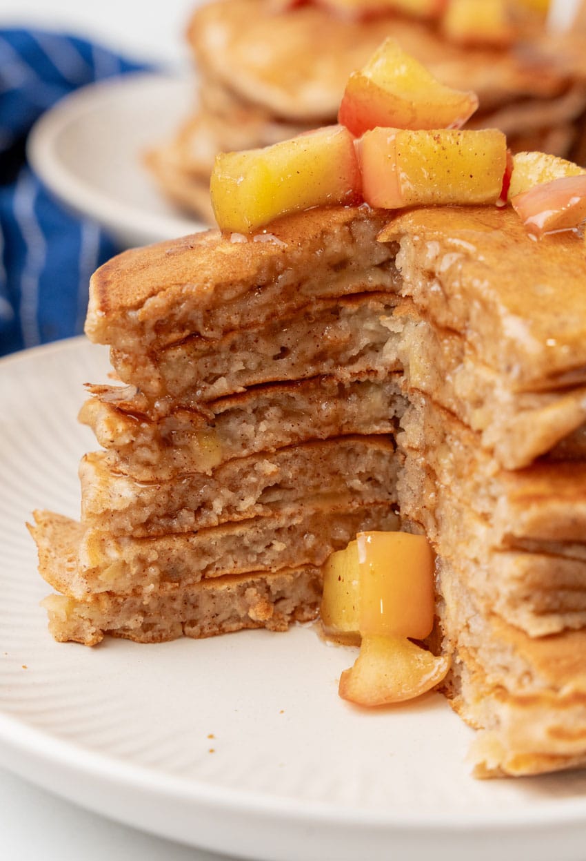 a stack of cut apple pie pancakes on a white plate