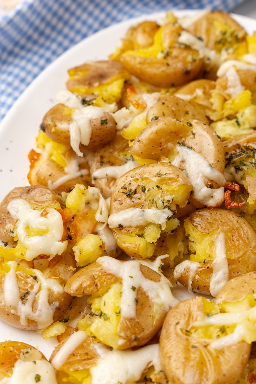 cheesy garlic cracked potatoes on a white serving platter