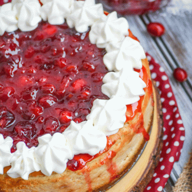 cranberry sauce topped eggnog cheesecake on a wooden cutting board