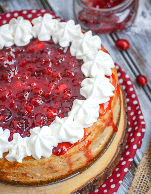 cranberry sauce topped eggnog cheesecake on a wooden cutting board