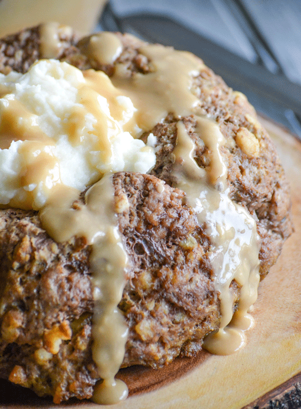 stovetop stuffing mix meatloaf with mashed potatoes in the center and drizzled with gravy on a wooden cutting board