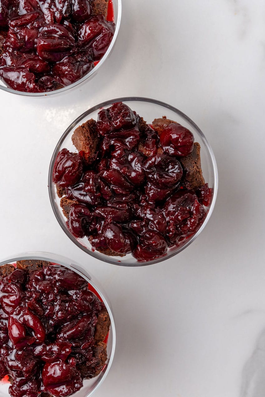 sweet dark cherry preserves over chopped brownie bits in a small glass bowl