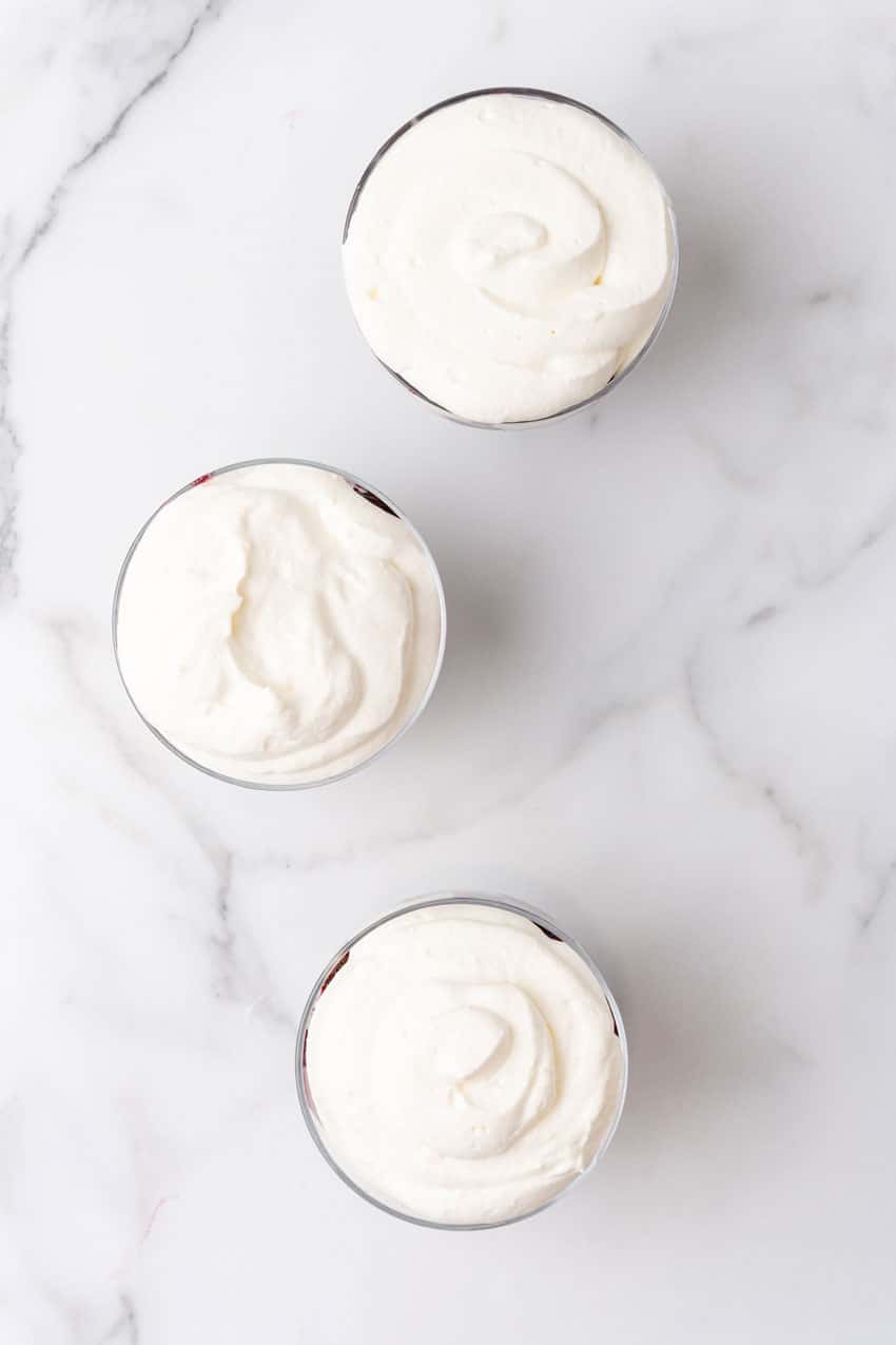 black forest cherry cheesecake layered in small glass bowls sitting on a marble countertop