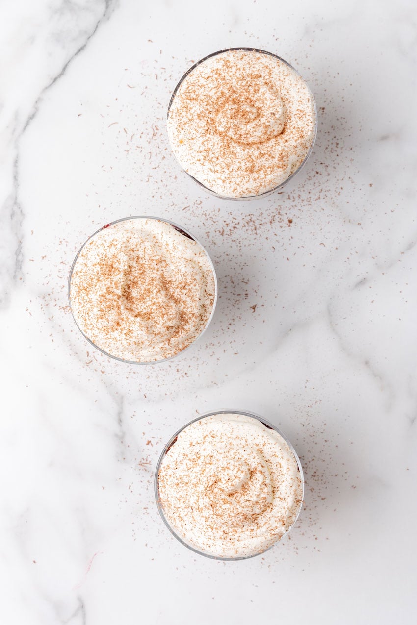 black forest cherry cheesecake layered in small glass bowls sitting on a marble countertop