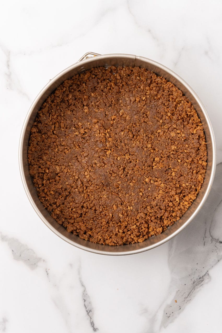 a baked graham cracker crust in the bottom of a spring lined pan