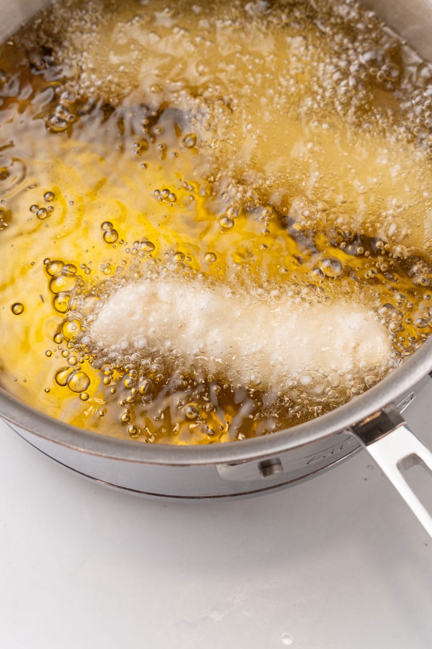 an eggroll frying in a pot of hot oil