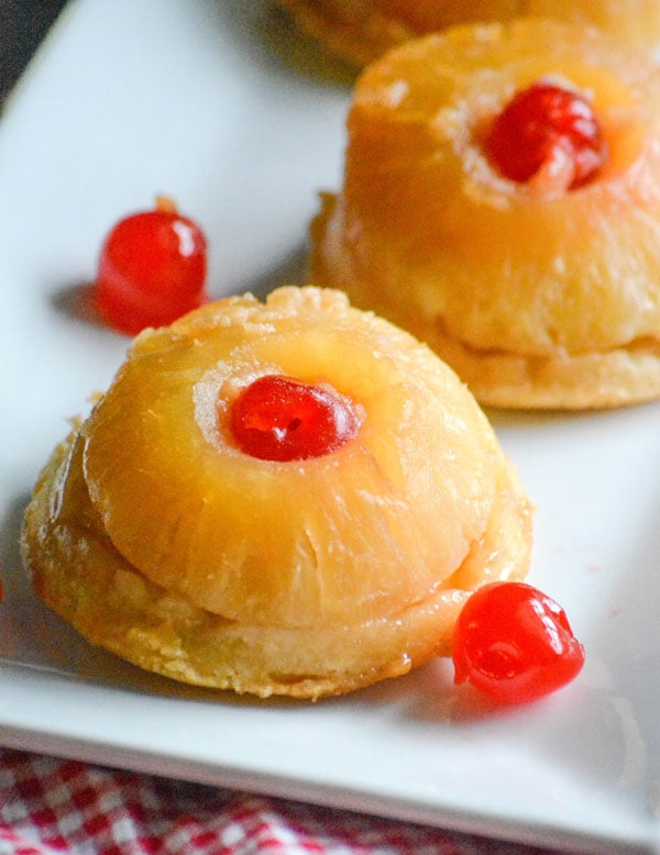 PINEAPPLE UPSIDE DOWN COOKIE CAKES ON A WHITE SERVING PLATTER WITH MARASCHINO CHERRIES ON THE SIDE