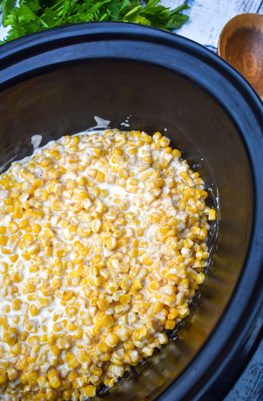 slow cooker creamed corn in the black bowl of a crockpot