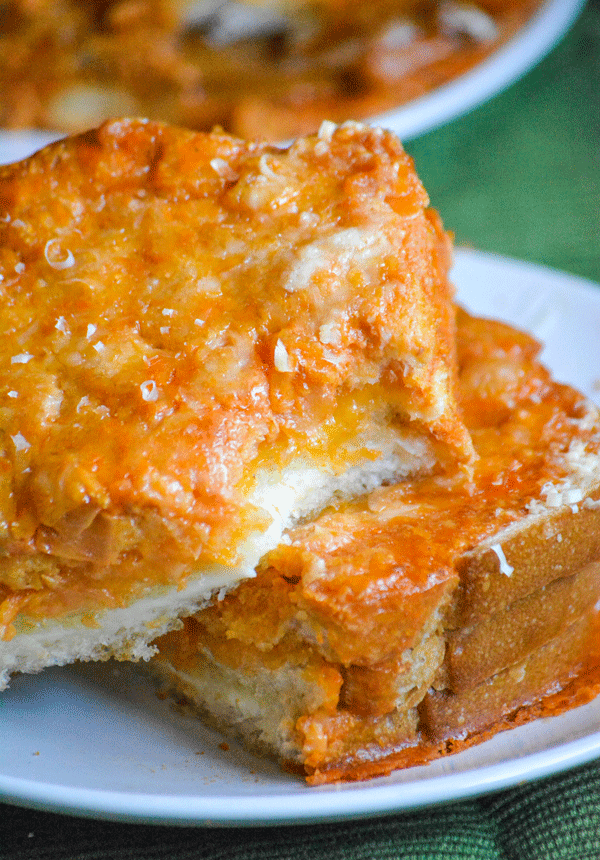 two slices of tomato soup dipped grilled cheese stacked on a white plate