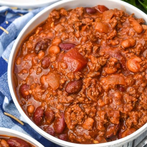 sweet and spicy chili in two white bowls with a plate of cornbread in the background