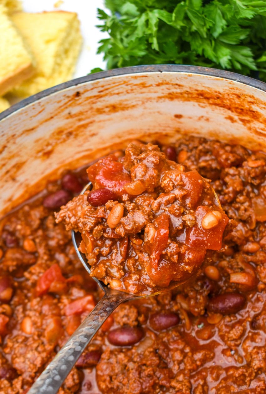 a silver ladle holding up a scoop of sweet and spicy chili