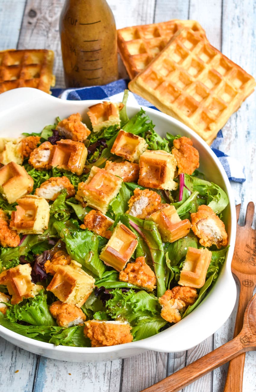 chicken and waffle salad with maple dijon vinagrette dressing in a large white serving bowl