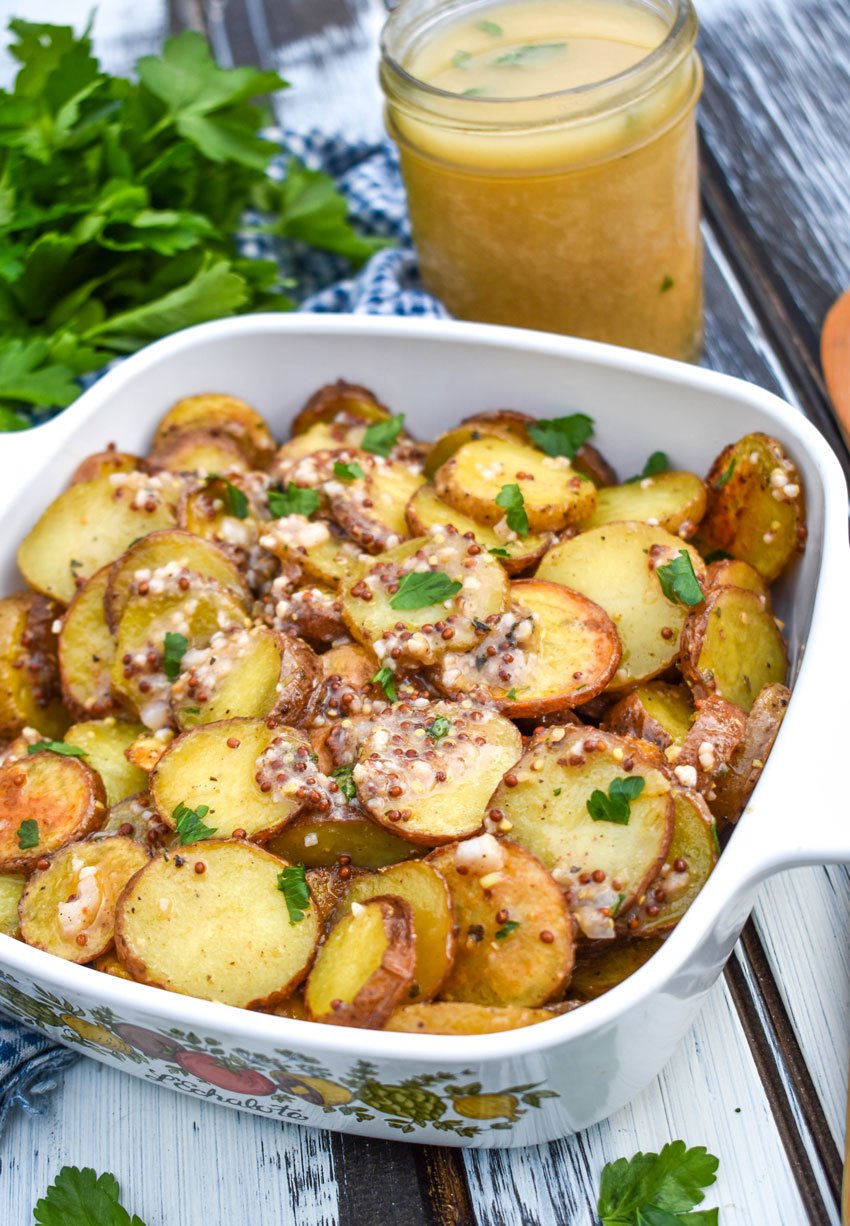 warm german potato salad topped with fresh herbs in a white pyrex baking dish