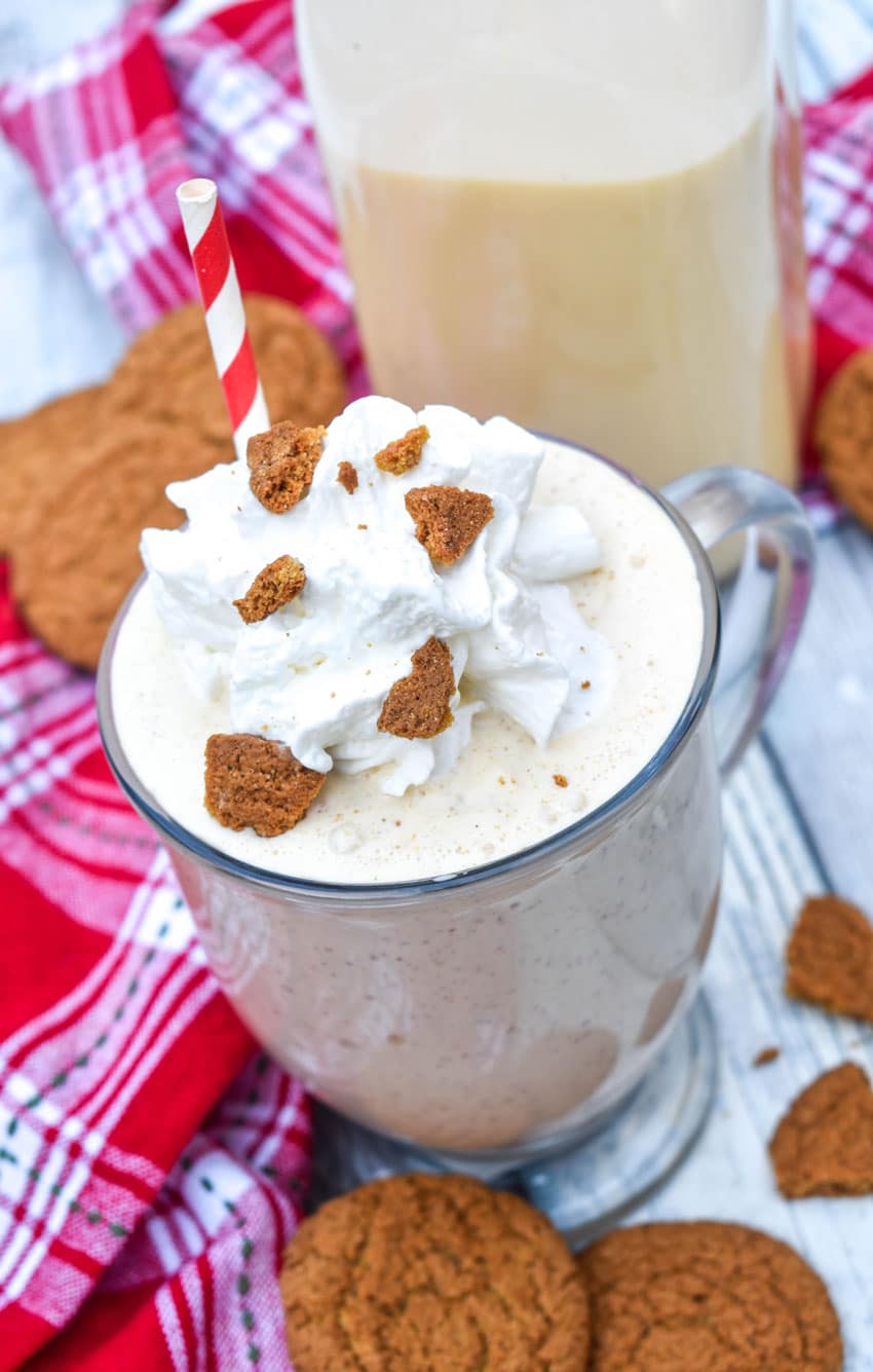 a gingerbread milkshake in a glass mug topped with whipped cream and gingersnap cookie crumbles