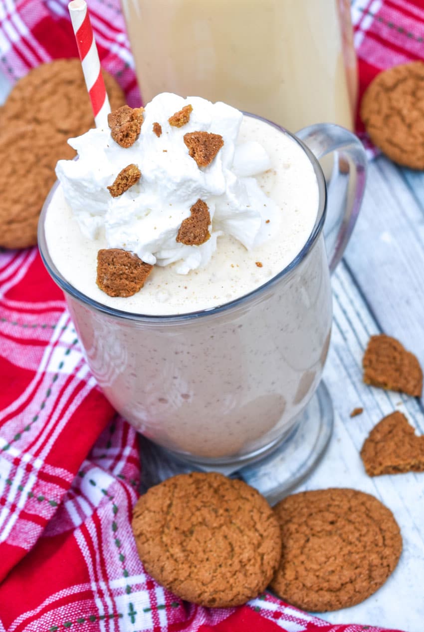 a gingerbread milkshake in a glass mug topped with whipped cream and gingersnap cookie crumbles