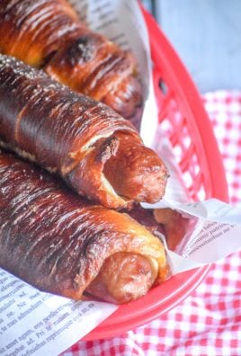 THREE EASY HOMEMADE PRETZEL DOGS IN A PAPER LINED RED FOOD BASKET