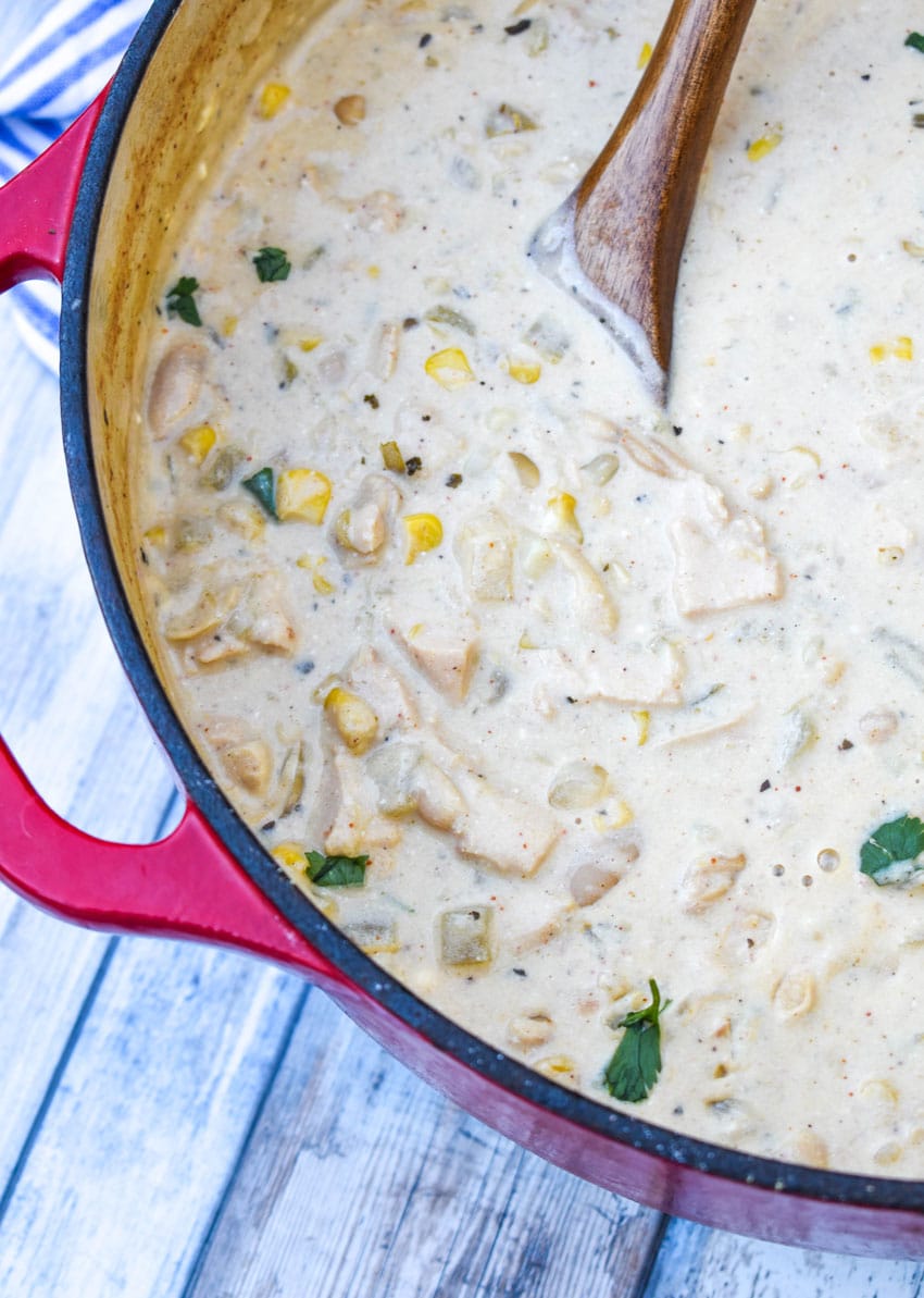 a wooden spoon resting in a pot of creamy white chicken chili