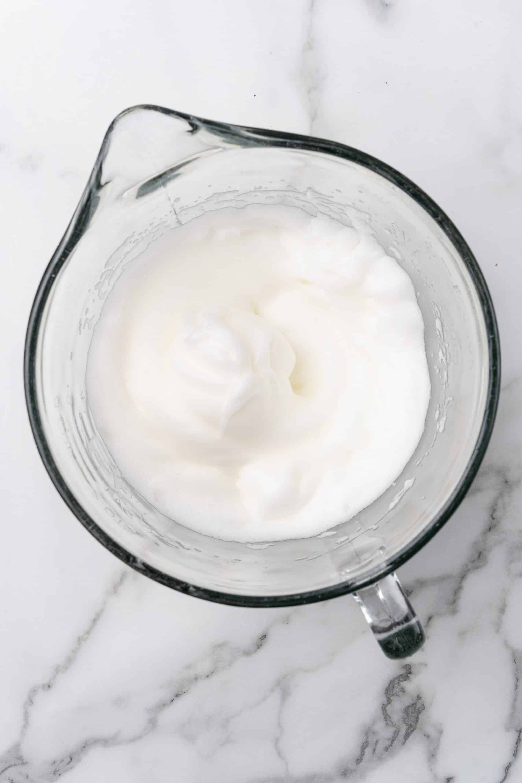 whipped egg whites in a glass mixing bowl