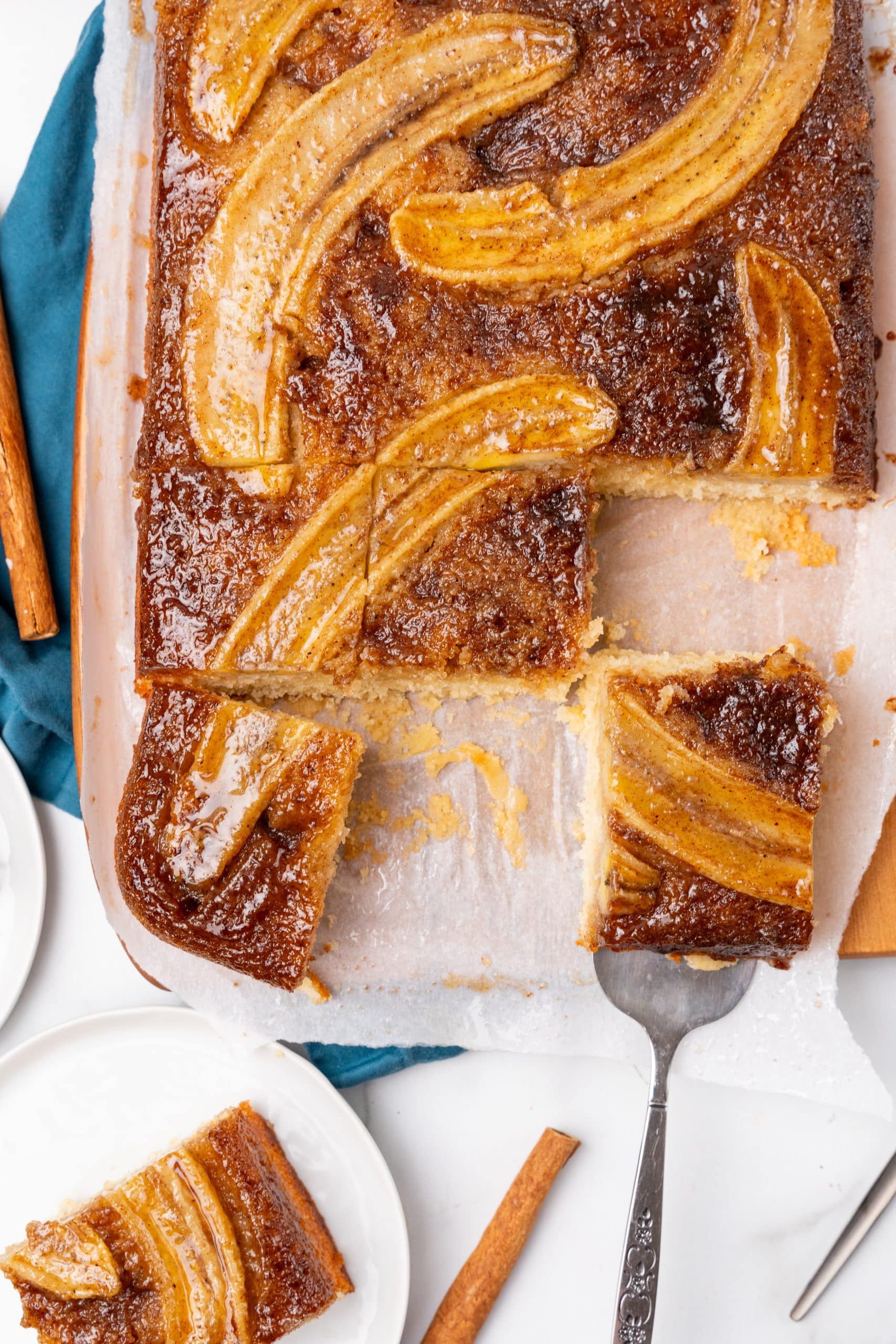 cut squares of bananas foster upside down cake on a parchment paper lined wooden cutting board