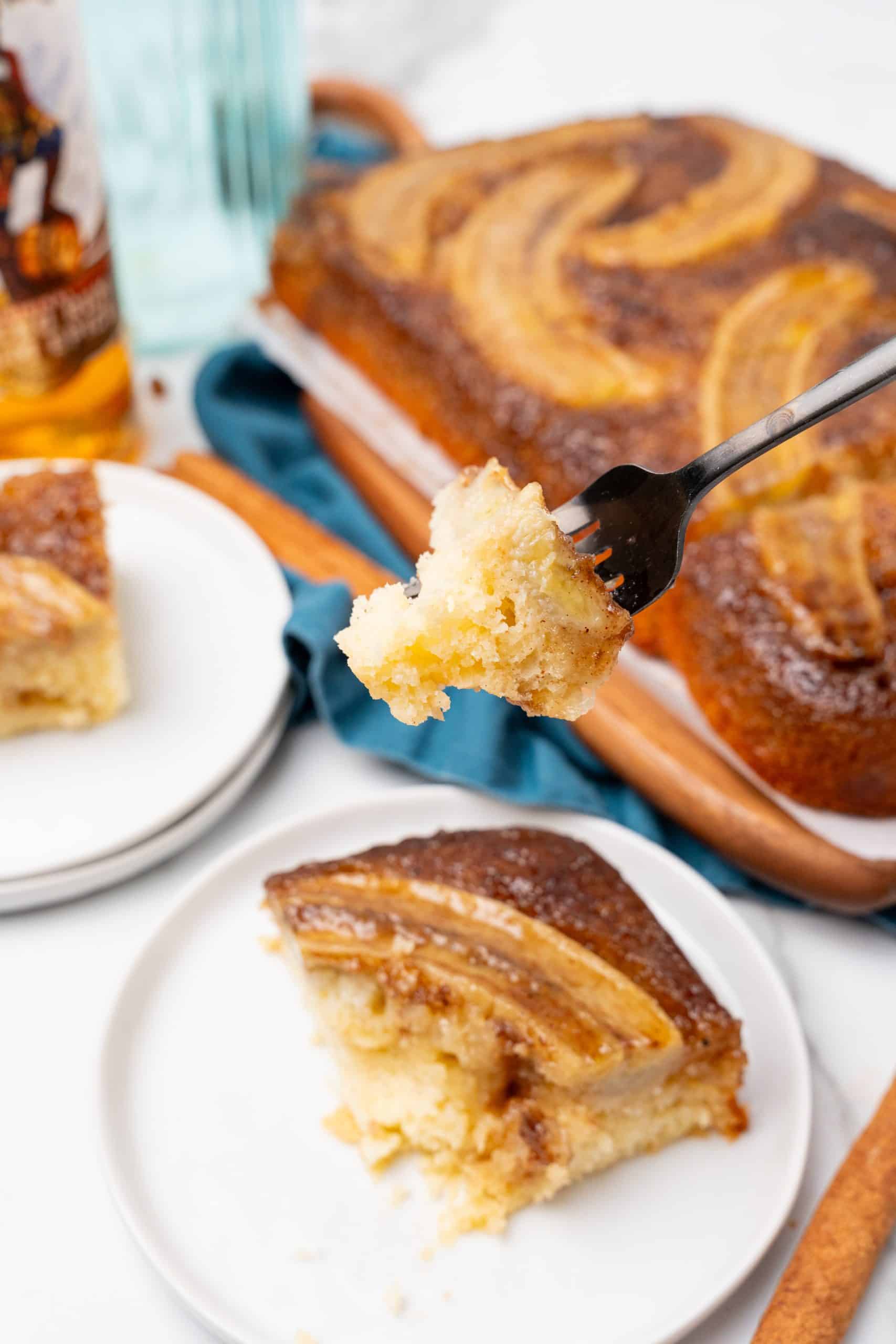 a black fork holding up a piece of bananas foster upside down cake
