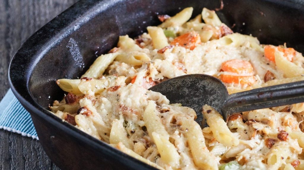 chicken noodle soup casserole shown being scooped from a black casserole dish