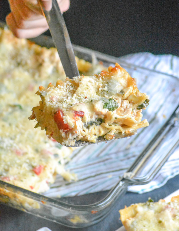 a slice of Chicken Caesar Lasagna being held aloft on a silver spatula