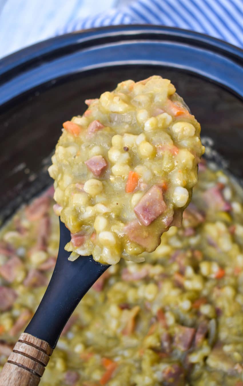 a black spoon holding up a scoop of crockpot split pea soup