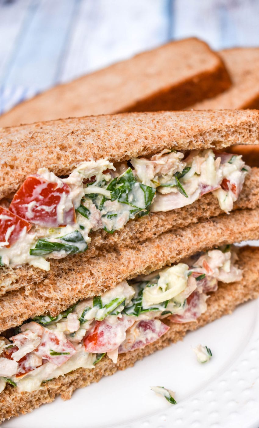 two halves of a tuna salad sandwich stacked together on a white plate