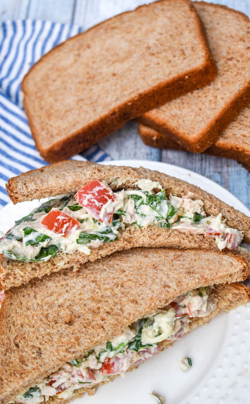 two halves of a tuna salad sandwich stacked together on a white plate