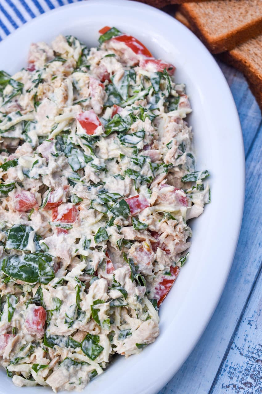 spinach and tomato tuna salad with greek yogurt in a white serving bowl