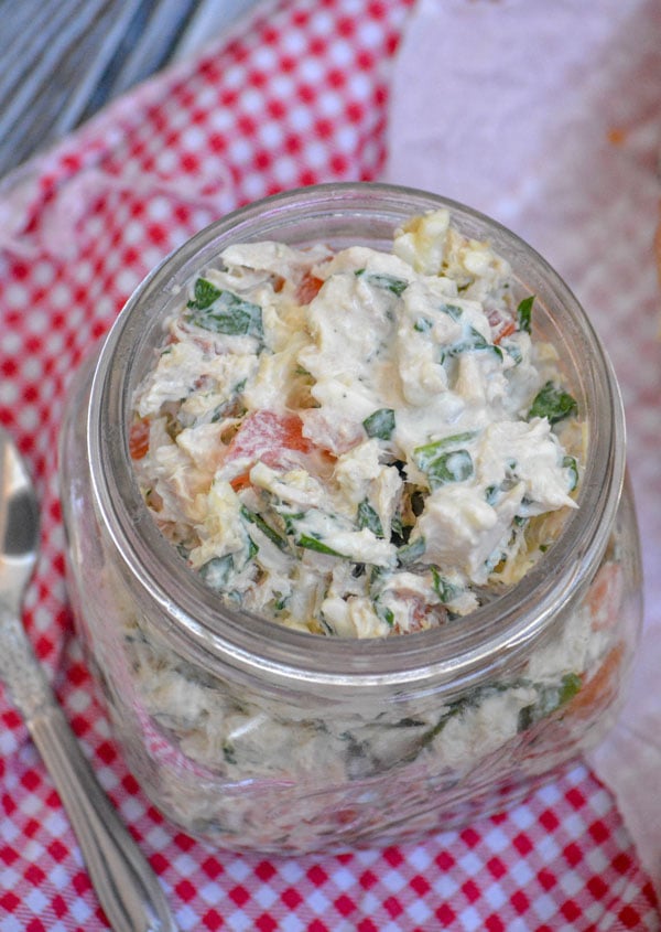 Spinach & Tomato Tuna Salad shown in a glass mason jar with a spoon on the side