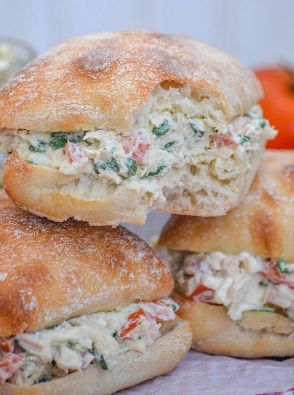 Spinach & Tomato Tuna Salad Sandwiches stacked together, and the top one has a bite taken out of it to show the filling