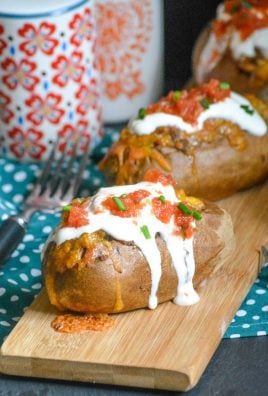 twice baked tex mex stuffed potatoes arranged in a line on a narrow wooden cutting board