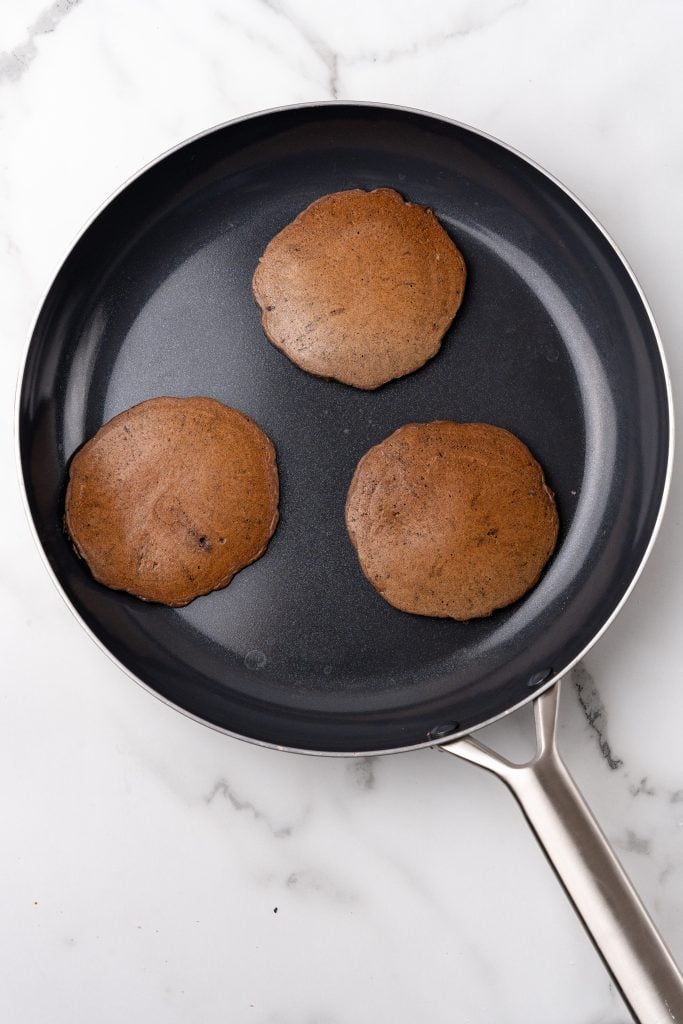 chocolate oreo pancakes cooking in a black skillet