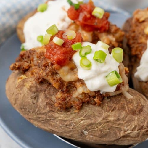 twice baked taco baked potatoes on a blue dinner plate