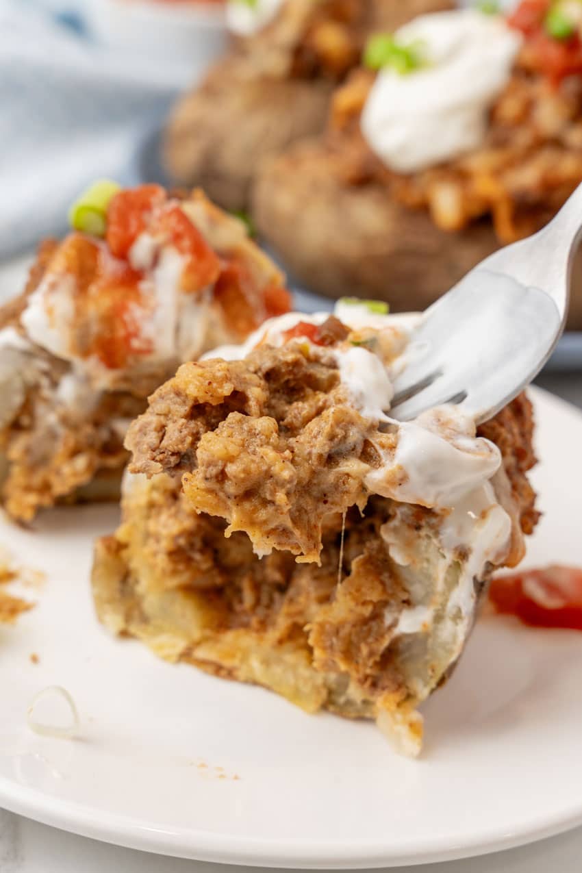 a silver fork holding up a scoop of cheesy taco potato filling