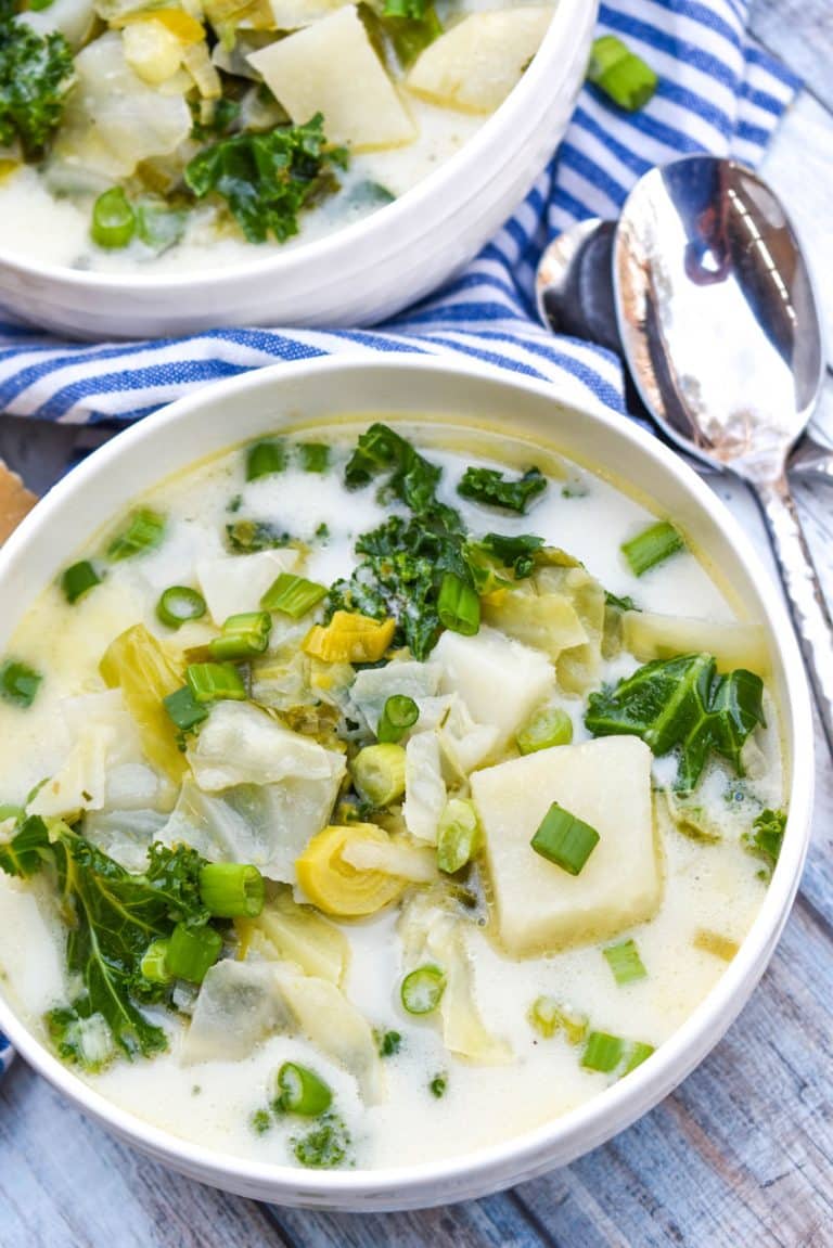 colcannon potato soup in two white bowls with slices of fresh baguette on the sides