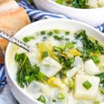 colcannon potato soup in two white bowls with slices of fresh baguette on the sides
