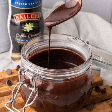 a silver spoon covered in Bailey's Irish cream chocolate sauce dripping into a glass jar