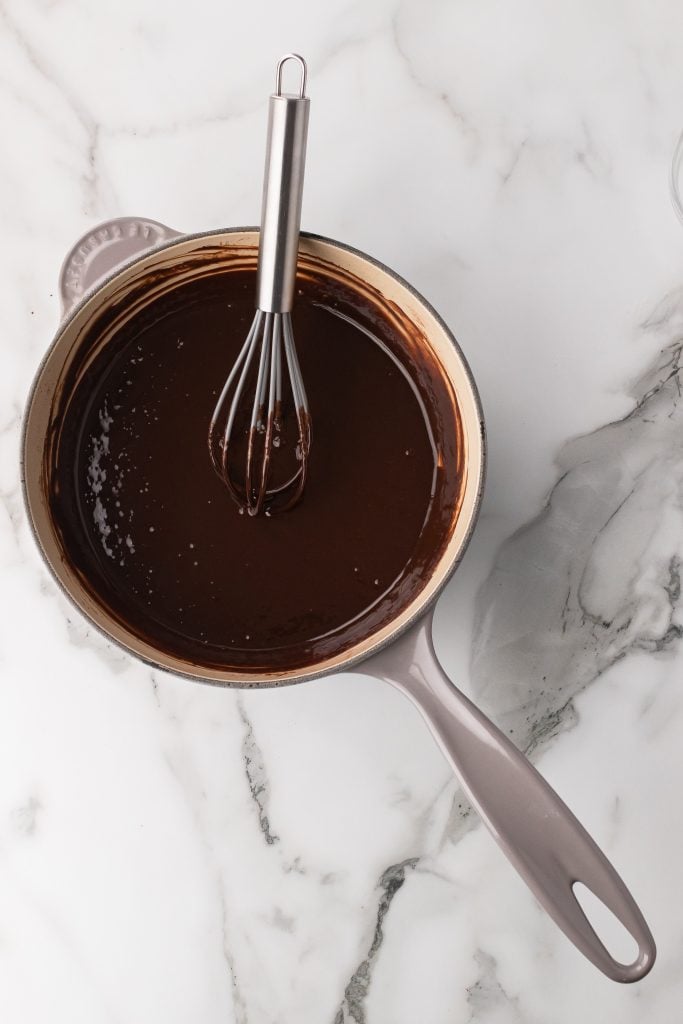 a silver whisk in a sauce pan with chocolate sauce