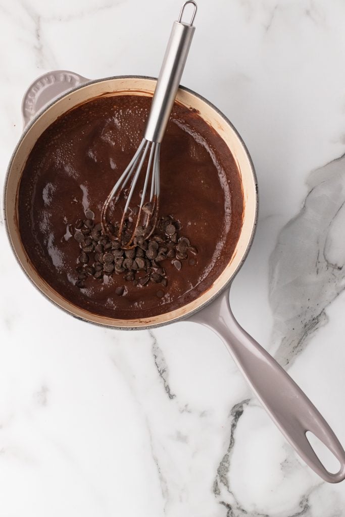 a silver whisk in a sauce pan with chocolate sauce