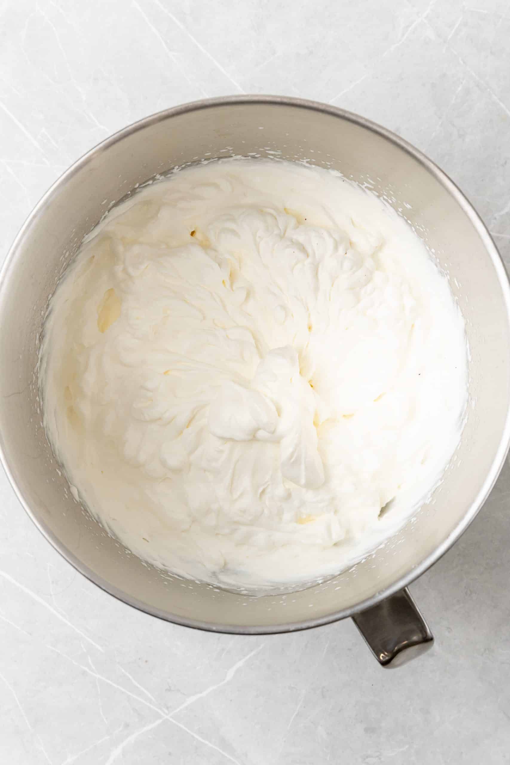 freshly whipped cream in a large metal mixing bowl