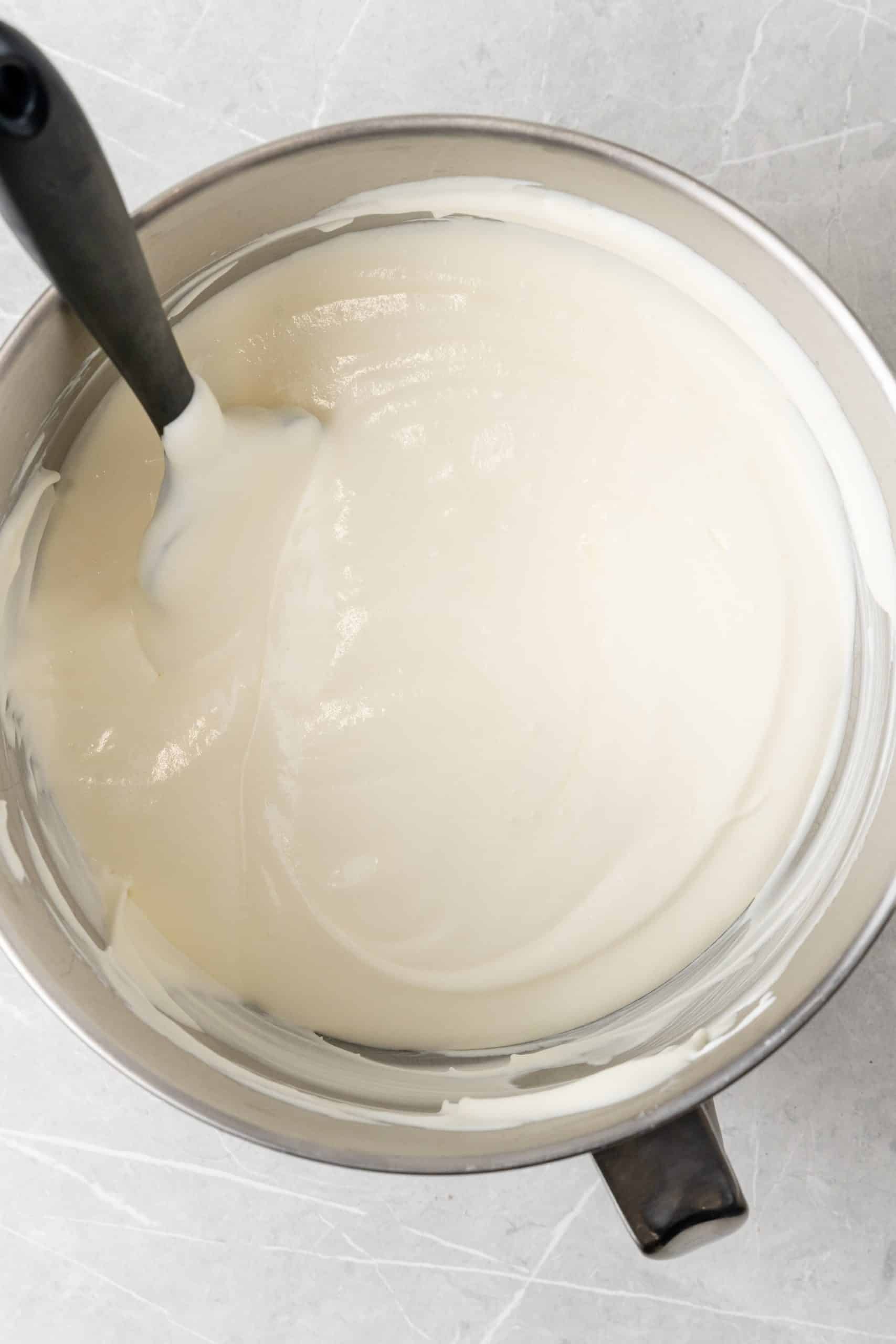 sweetened condensed milk mixed with whipped cream in a large metal mixing bowl
