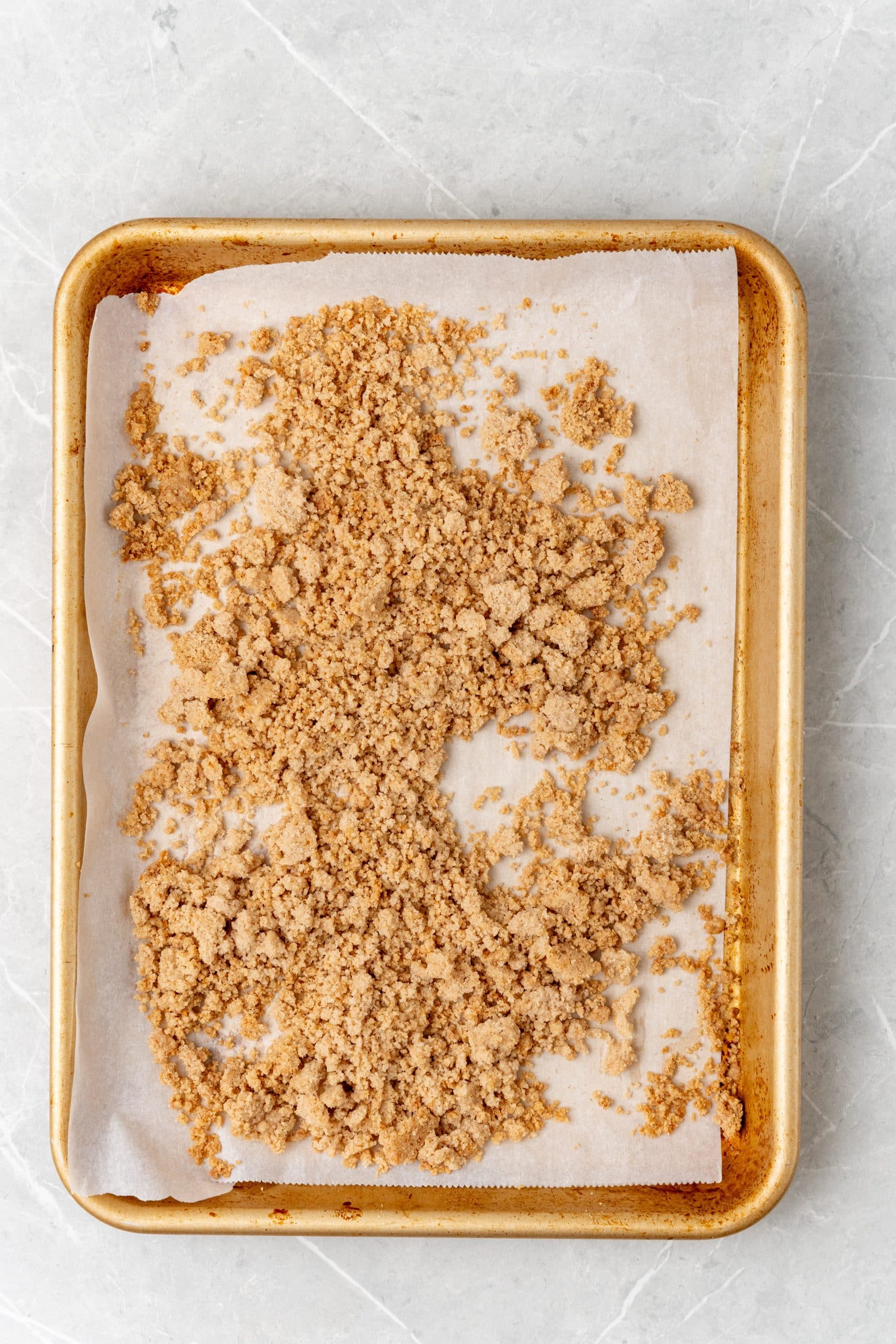 broken up baked bits of homemade streusel on a parchment paper lined baking sheet 