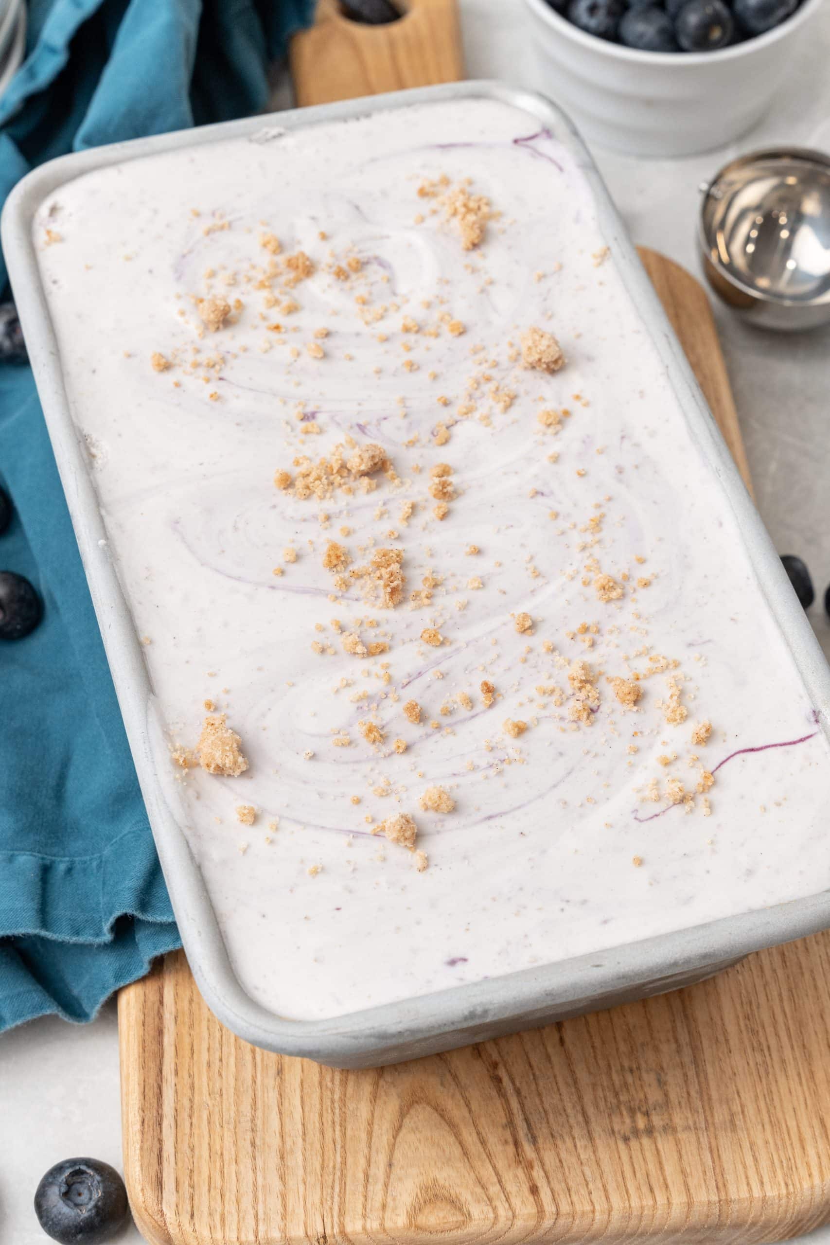 no churn blueberry muffin ice cream in a metal baking tin on a wooden cutting board